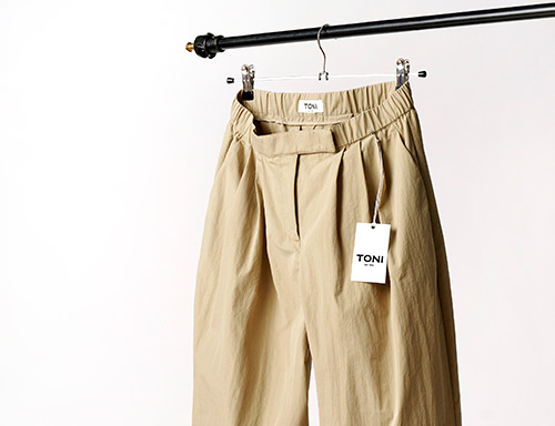 Beigefarbene TONI Hose mit Etikett auf Kleiderbügel – Teaser zur internationalen Retoure für Kundinnen aus den Niederlanden
