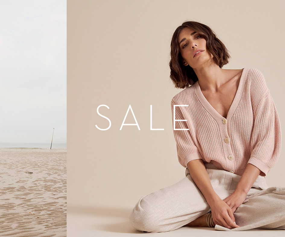 Frau in roséfarbenem TONI-Strick sitzt entspannt – Mobile-Teaser zum Summer Sale.