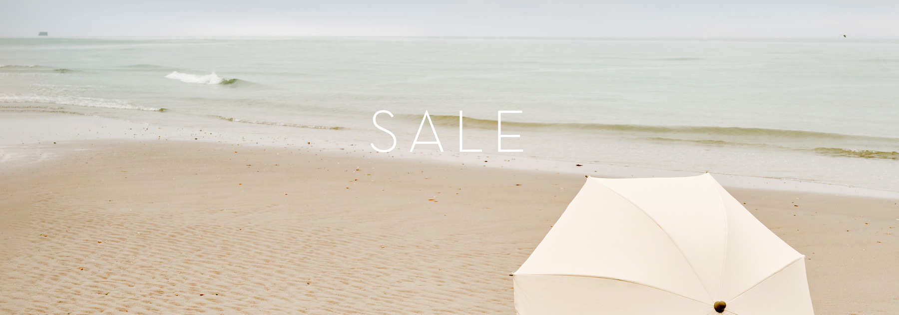 Heller Schirm am leeren Strand – stimmungsvoller Teaser zum Summer Sale bei TONI.
