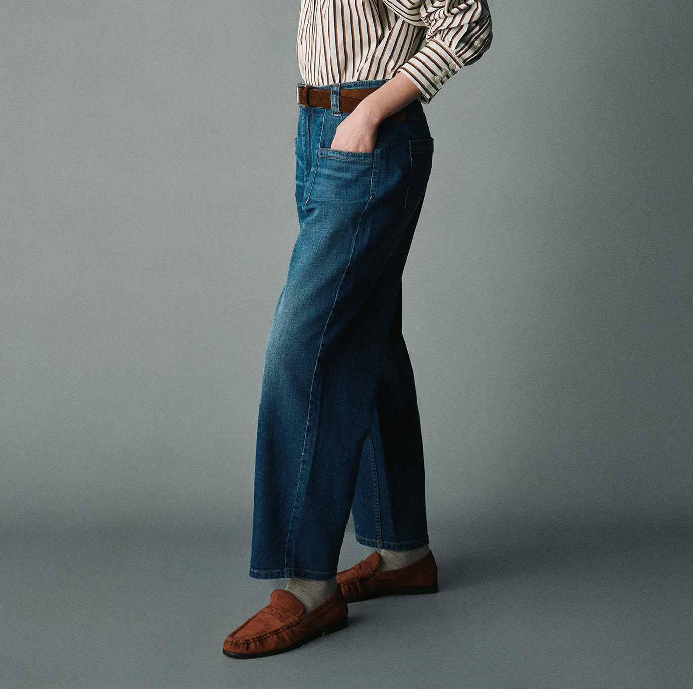 Model wearing blue TONI jeans with a wide cropped leg, styled with a striped blouse and brown loafers.