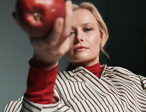 Model holding a red apple – return registration for orders from Austria.