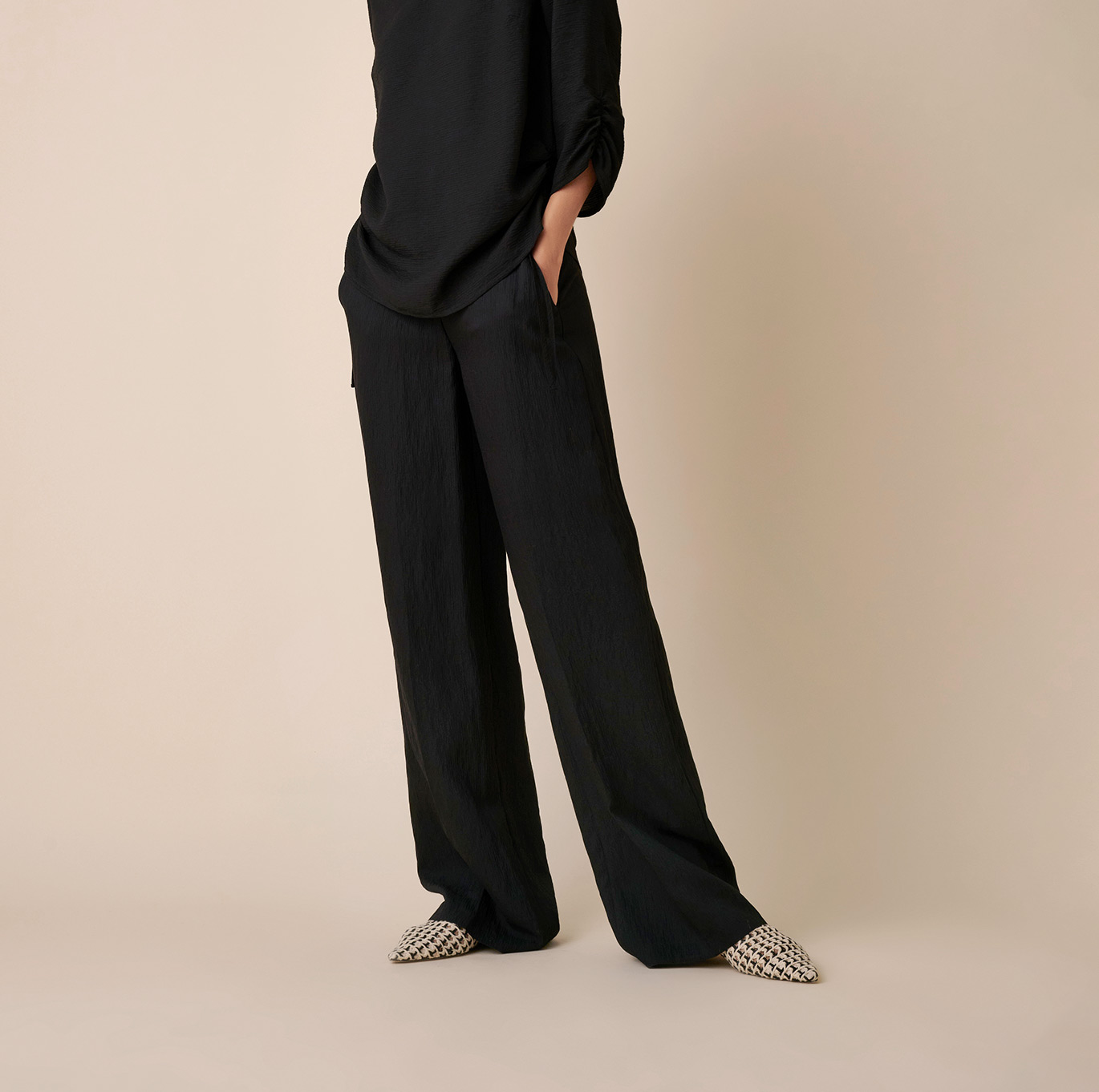 Frau in schwarzer weiter TONI-Hose und monochromem Look – Teaser zur Kategorie Hosen.