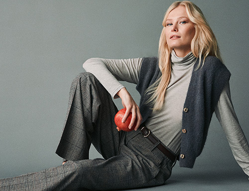 Model wearing a grey TONI look with a red apple – return registration for orders from the Netherlands.